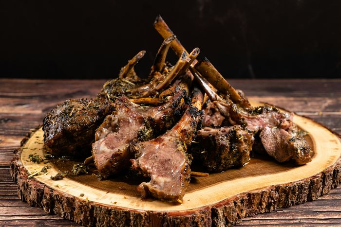 Lamb cutlets, charred from the fire, on a board